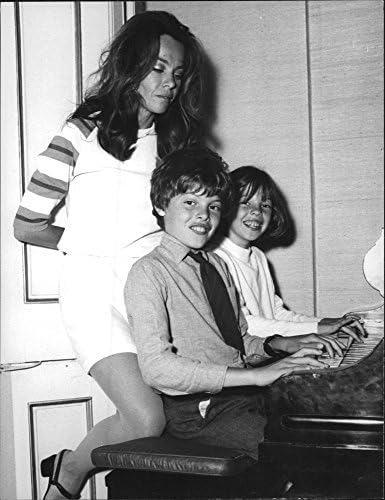 תצלום וינטג 'של לסלי קארון עם ילדיה משחקים בפסנתר.